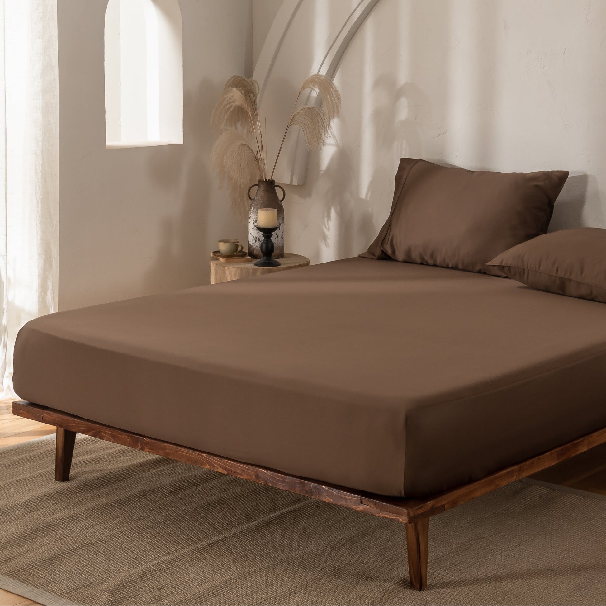 Brown bamboo bedding with matching pillows in a minimalistic room with wooden floor and white walls.