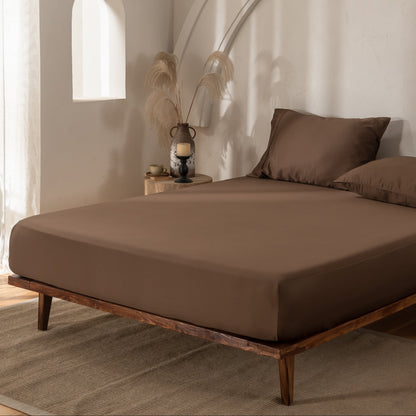Brown bamboo bedding with matching pillows in a minimalistic room with wooden floor and white walls.