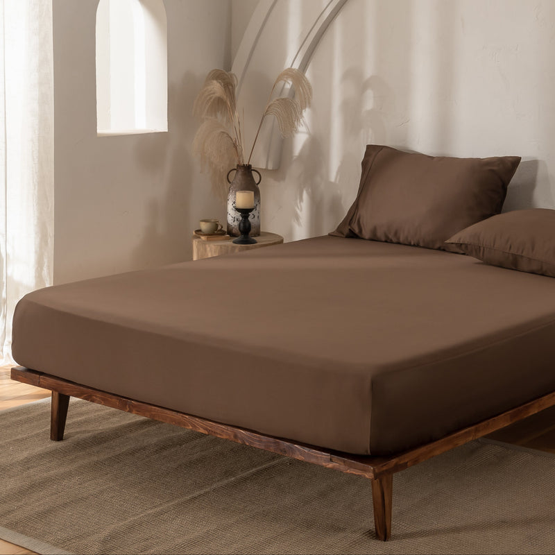 Brown bamboo bedding with matching pillows in a minimalistic room with wooden floor and white walls.