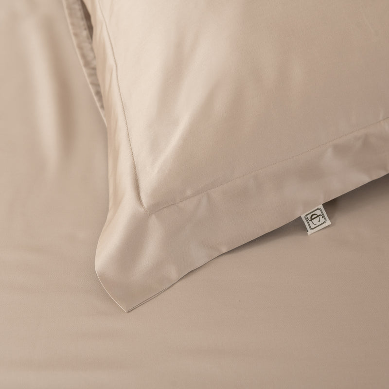 Close-up of beige pillow with brand logo tag on a matching fabric background